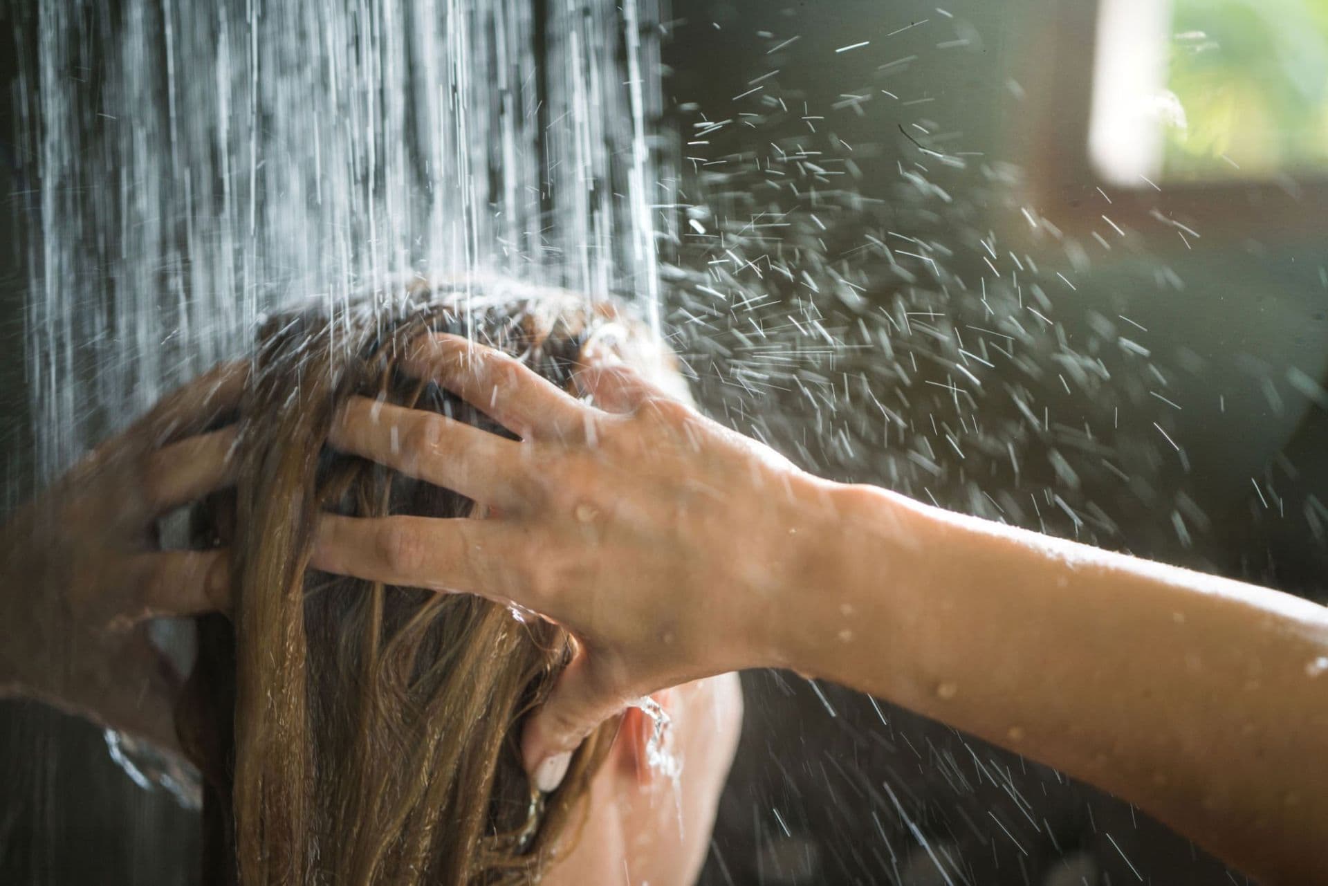 Woman washing hair under a rain style shower head