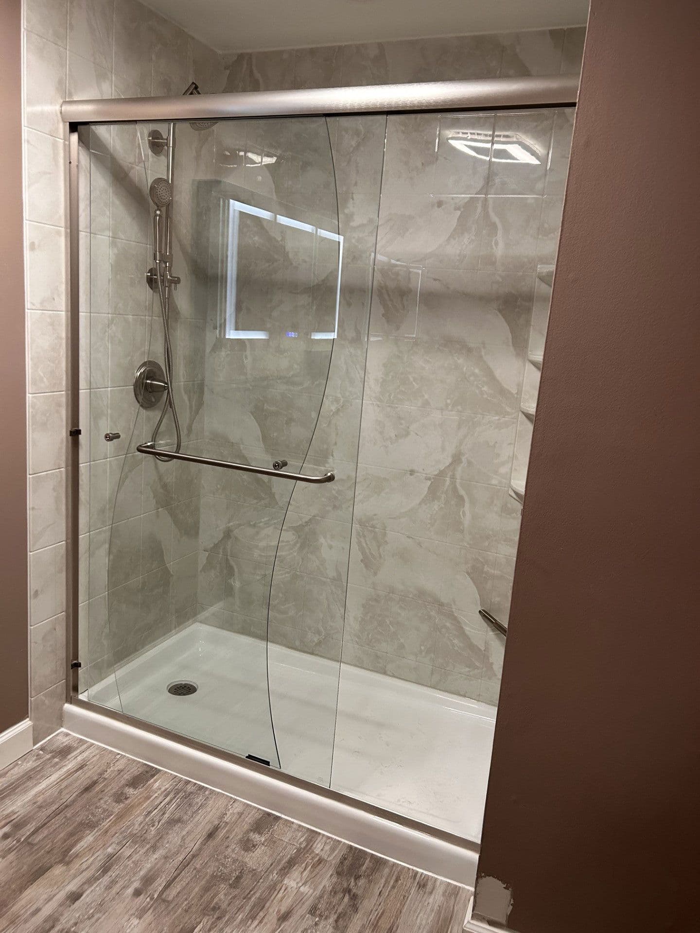 A stylish walk-in shower with no threshold, bordered glass, and a frameless glass door.