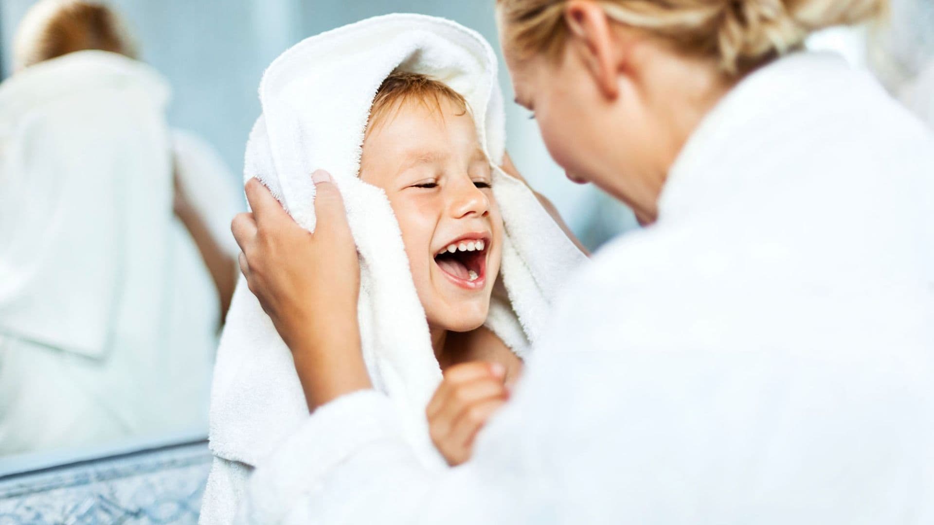 Mother towels off happy toddler after Bath time